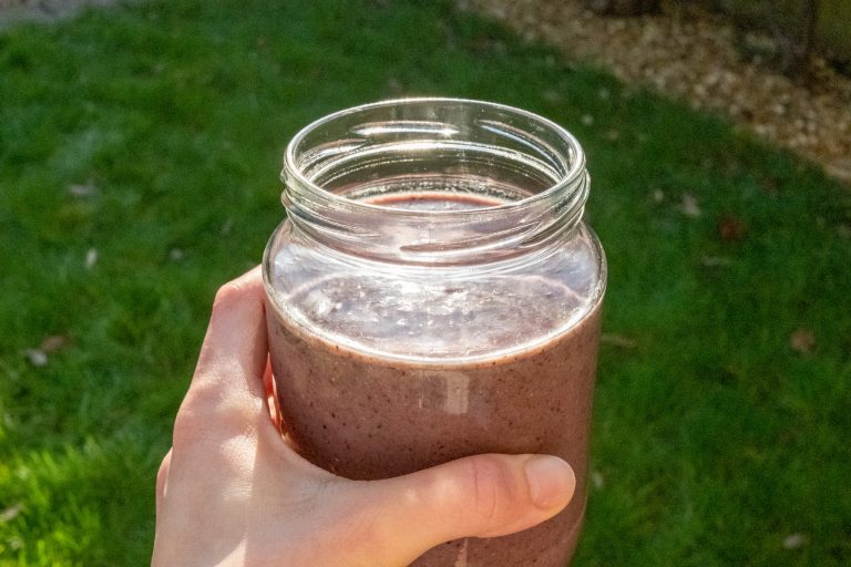 Healthy, vegan, berry smoothie being enjoyed in the garden for breakfast.